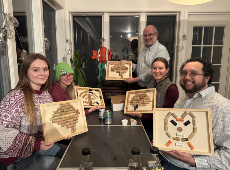 lab members holding art pieces made of wine corks at the lab holiday party 2024